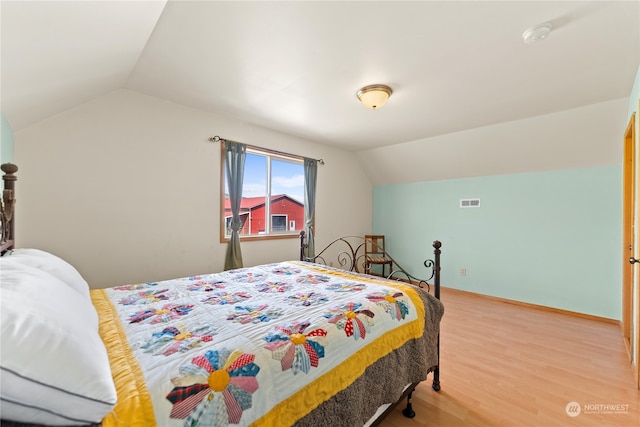 bedroom featuring light hardwood / wood-style flooring and lofted ceiling