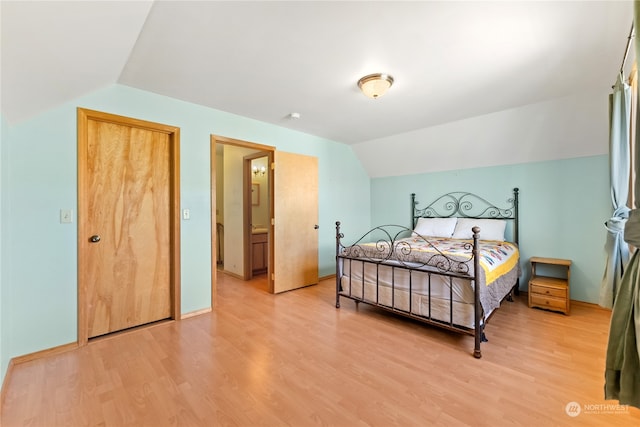 bedroom with vaulted ceiling, light hardwood / wood-style flooring, and ensuite bath