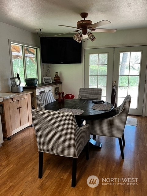 dining space with a textured ceiling, ceiling fan, and dark wood-type flooring