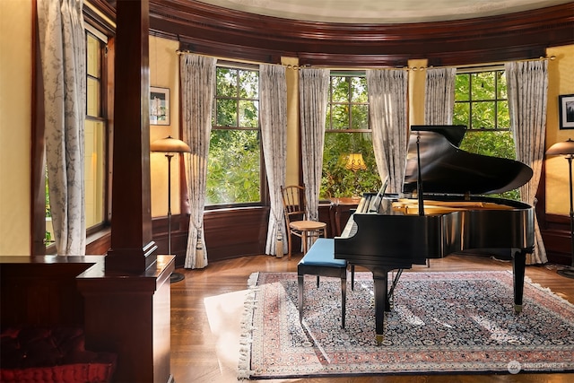 misc room with a healthy amount of sunlight, ornate columns, ornamental molding, and parquet flooring