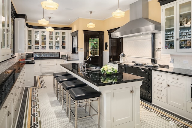 kitchen featuring an island with sink, a breakfast bar area, island exhaust hood, tasteful backsplash, and light tile floors