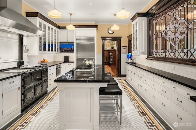 kitchen featuring stainless steel built in refrigerator, white cabinets, wall chimney exhaust hood, and tasteful backsplash