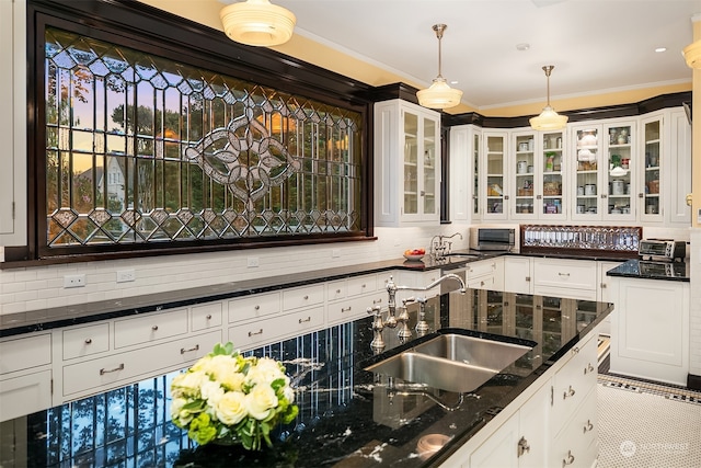 kitchen featuring decorative light fixtures, dark stone counters, backsplash, sink, and light tile floors