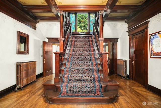 stairs with beamed ceiling, coffered ceiling, and radiator heating unit