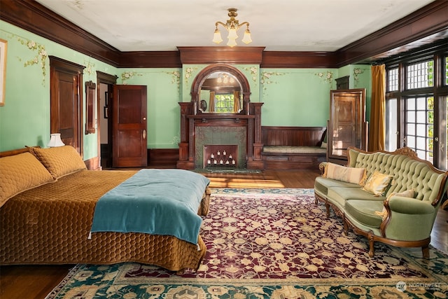 bedroom featuring crown molding, hardwood / wood-style flooring, a fireplace, and a chandelier