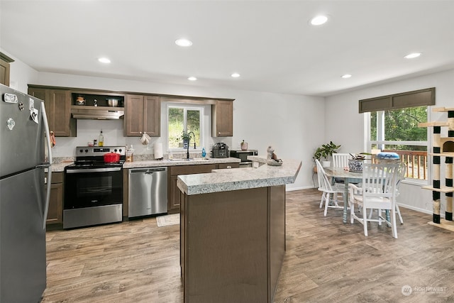 kitchen with appliances with stainless steel finishes, a kitchen island, sink, light hardwood / wood-style floors, and dark brown cabinets