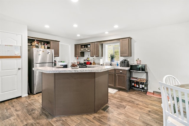 kitchen featuring dark brown cabinets, light hardwood / wood-style floors, stainless steel appliances, and a kitchen island