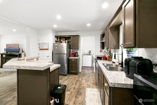 kitchen featuring dark brown cabinets, a kitchen island, light hardwood / wood-style flooring, stainless steel refrigerator, and sink