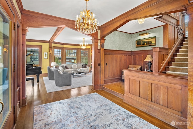 foyer with ornate columns, wood-type flooring, ornamental molding, and wooden walls