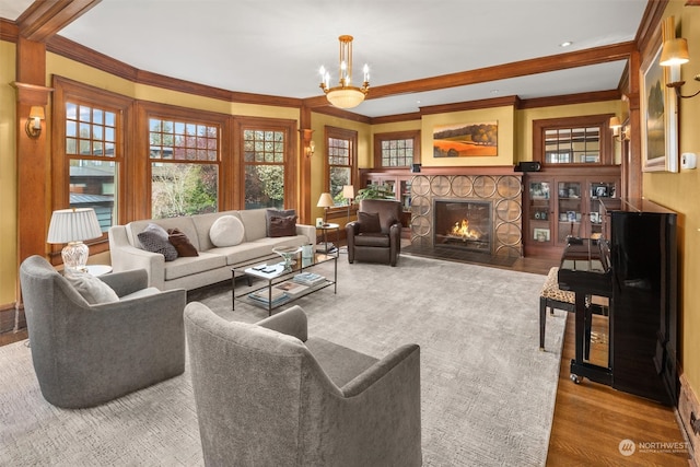 living room featuring a fireplace, ornamental molding, a notable chandelier, and light wood-type flooring