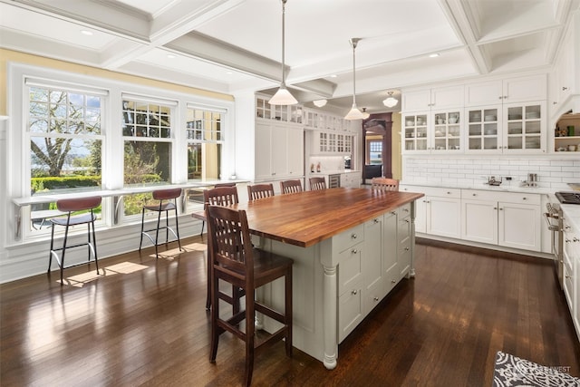 kitchen with a kitchen island, dark wood-type flooring, hanging light fixtures, white cabinetry, and wood counters