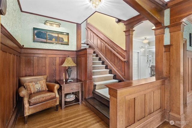 stairs featuring ornamental molding, hardwood / wood-style flooring, and ornate columns