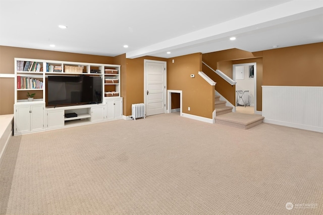 unfurnished living room with radiator, light colored carpet, and beam ceiling