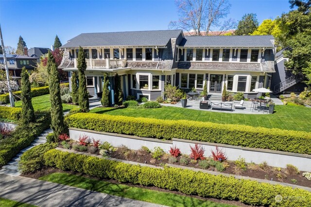 back of house featuring a patio, a lawn, and a balcony