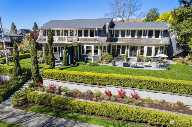 exterior space featuring a front yard, a balcony, outdoor lounge area, and a patio