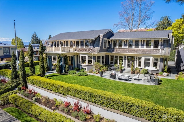 back of property featuring an outdoor living space, a yard, a balcony, and a patio area