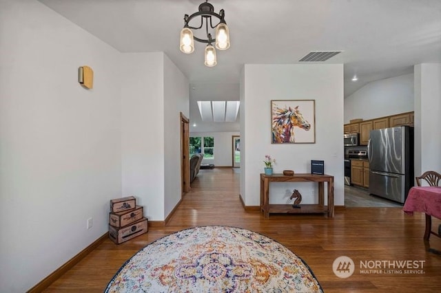 corridor featuring visible vents, baseboards, light wood-style flooring, and a chandelier