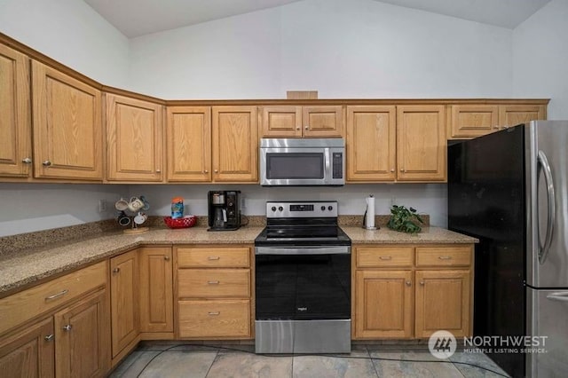 kitchen with appliances with stainless steel finishes, lofted ceiling, and light stone countertops