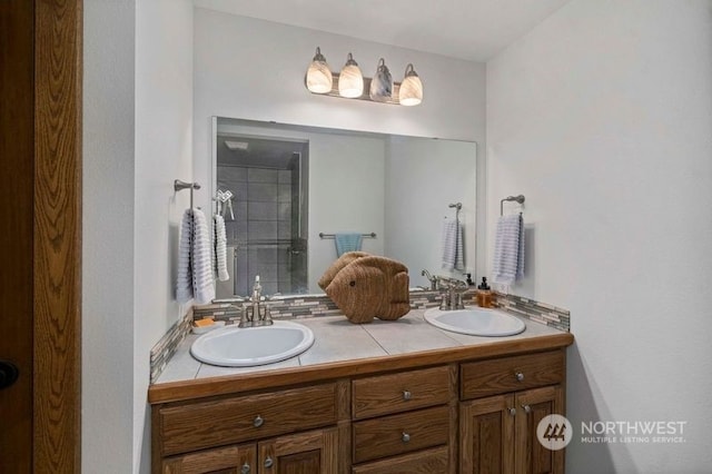 bathroom with double vanity, a tile shower, and a sink