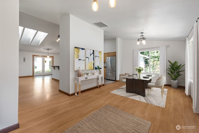 living room with french doors, light hardwood / wood-style flooring, a chandelier, and lofted ceiling with skylight