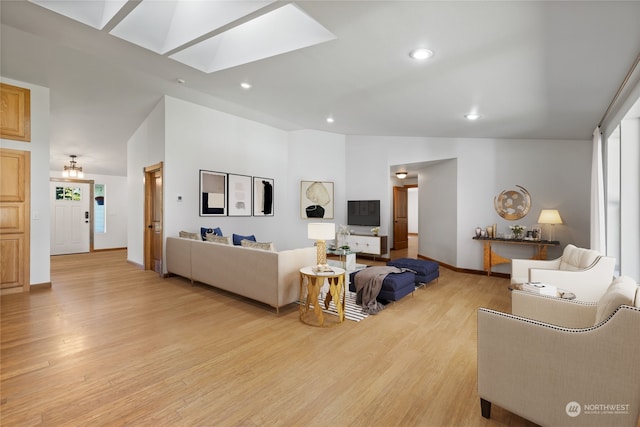 living room featuring light hardwood / wood-style flooring, high vaulted ceiling, and a skylight