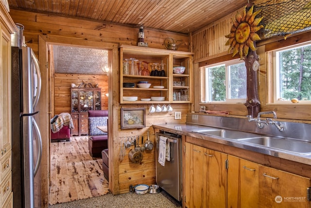 kitchen featuring stainless steel counters, appliances with stainless steel finishes, sink, and wood walls