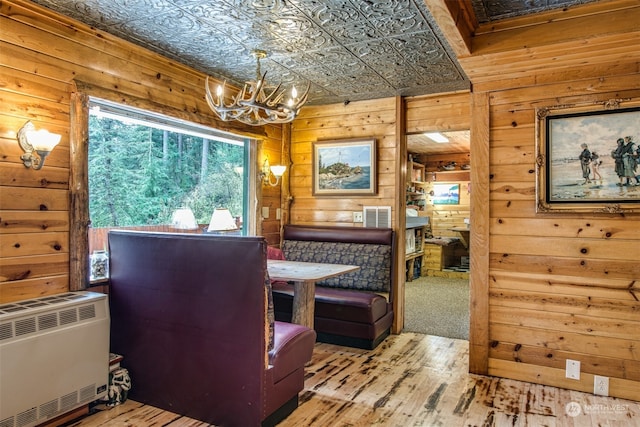 dining room featuring a chandelier, light hardwood / wood-style floors, heating unit, and wood walls