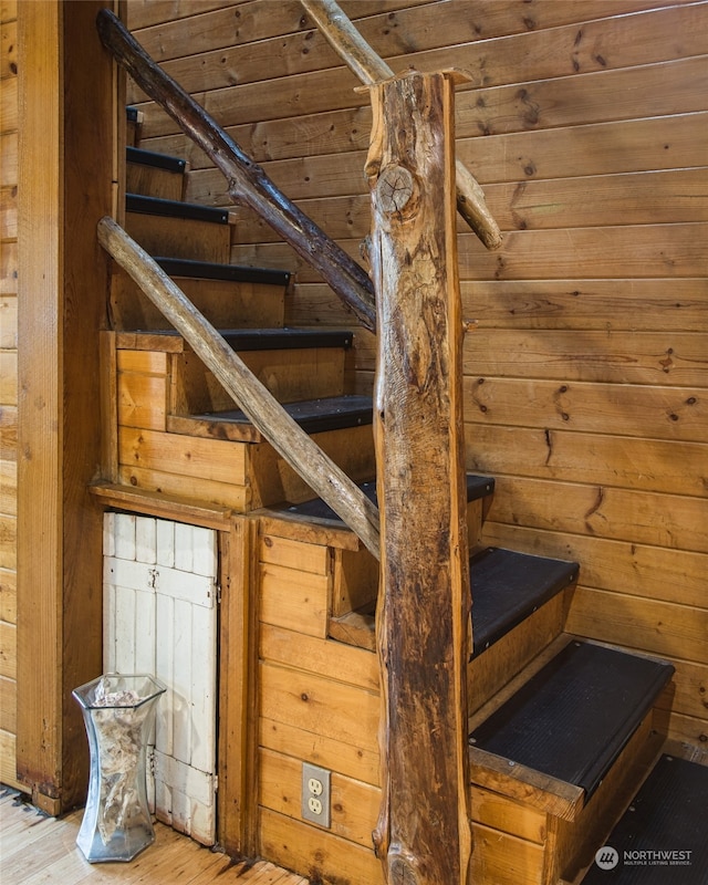 stairs featuring hardwood / wood-style flooring and wooden walls