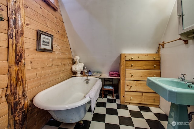 bathroom with wooden walls, a bath, and vaulted ceiling