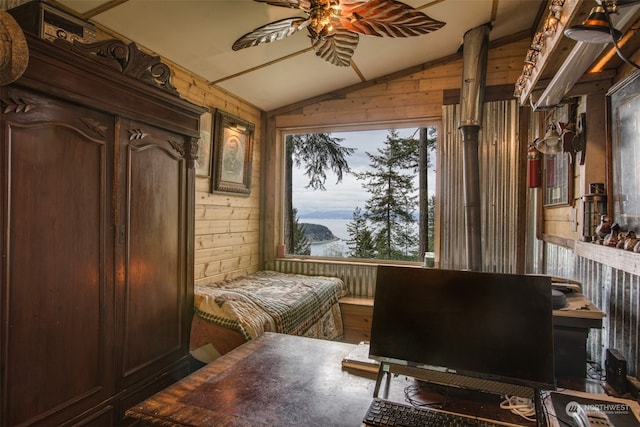 sitting room with vaulted ceiling, wooden walls, and ceiling fan