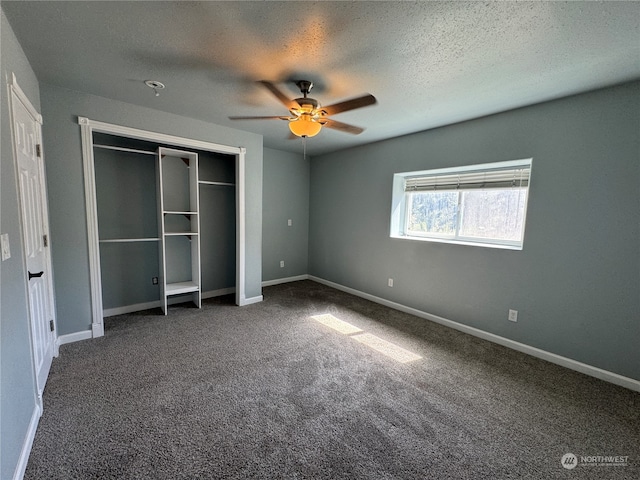 unfurnished bedroom featuring ceiling fan, dark carpet, and a textured ceiling