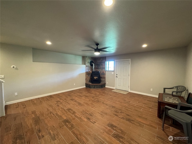 living area with ceiling fan, a wood stove, and dark hardwood / wood-style flooring