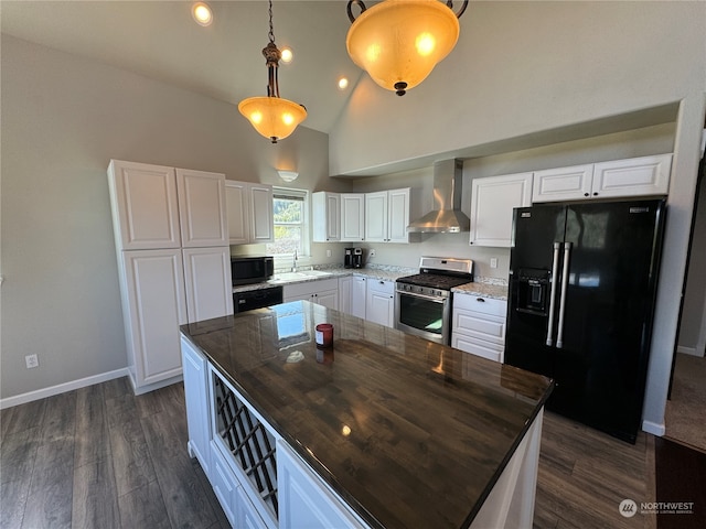 kitchen featuring decorative light fixtures, black appliances, wall chimney exhaust hood, white cabinets, and a center island