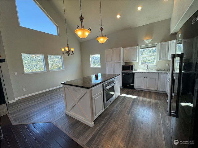 kitchen with white cabinets, dark hardwood / wood-style flooring, a center island, and black appliances