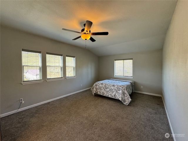 unfurnished bedroom with ceiling fan, lofted ceiling, and dark carpet