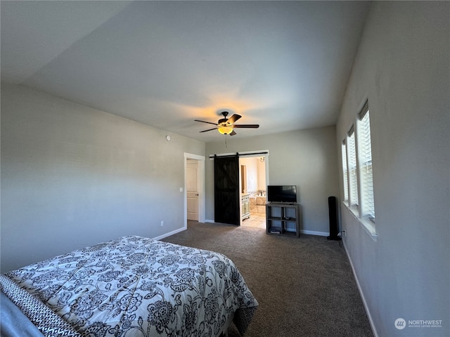 bedroom with carpet flooring, ceiling fan, connected bathroom, and a barn door