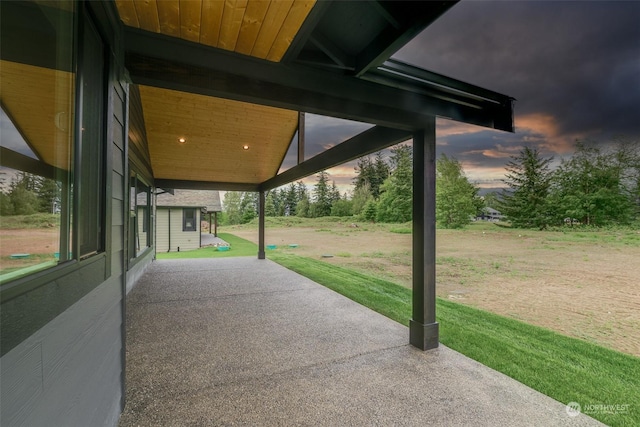 patio terrace at dusk featuring a yard