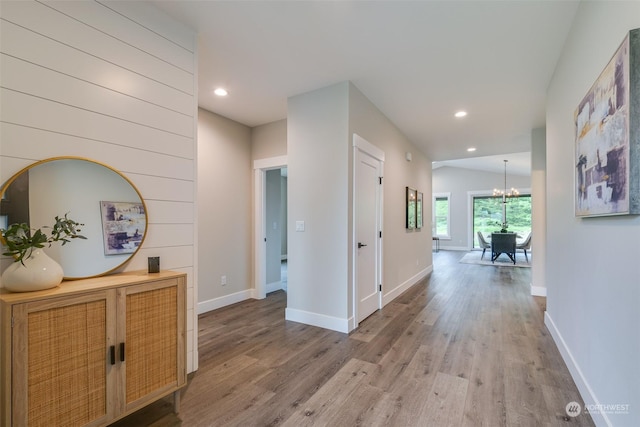 corridor with hardwood / wood-style floors and a chandelier