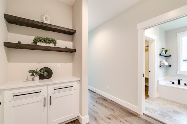 bar with white cabinetry and light hardwood / wood-style floors