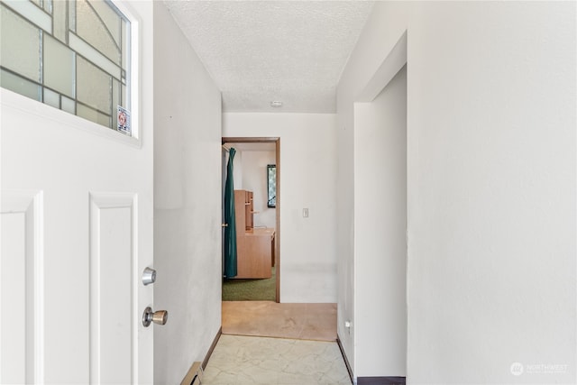 hallway featuring light colored carpet, a textured ceiling, and a baseboard radiator