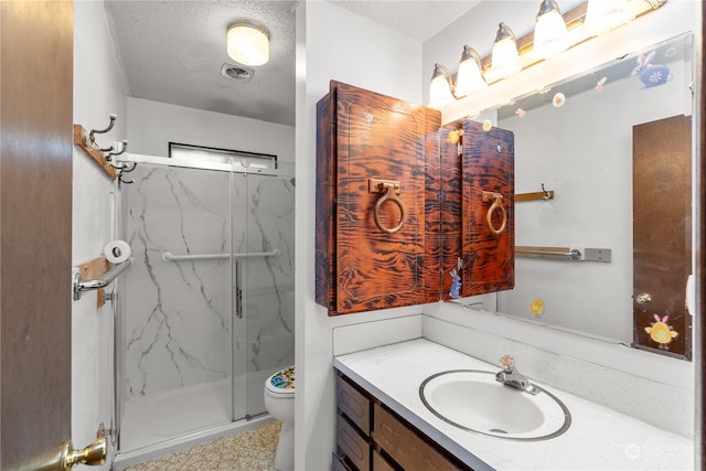 bathroom with a shower with door, vanity, toilet, and a textured ceiling