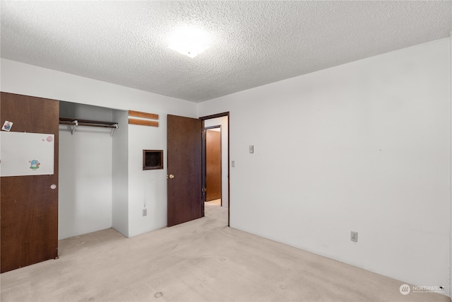 unfurnished bedroom with light carpet, a closet, and a textured ceiling