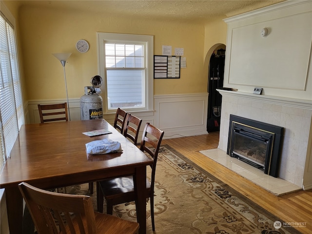 dining space with light hardwood / wood-style floors, a tile fireplace, and a textured ceiling