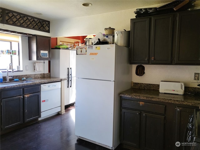 kitchen featuring dark brown cabinetry, white appliances, dark wood-type flooring, and sink