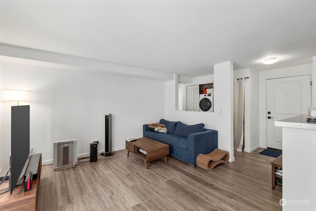 living room featuring hardwood / wood-style flooring and stacked washer / dryer