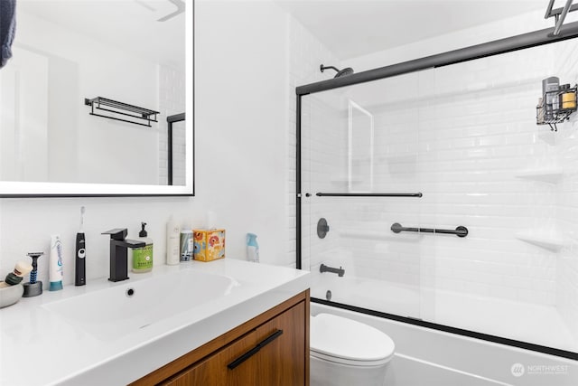 full bathroom featuring combined bath / shower with glass door, vanity, and toilet