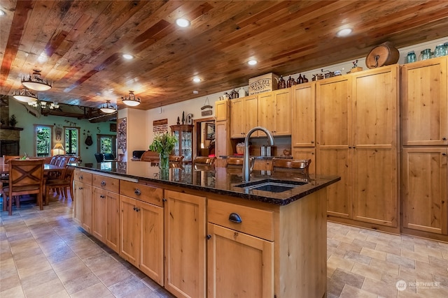 kitchen featuring sink, a center island with sink, light tile floors, and wooden ceiling