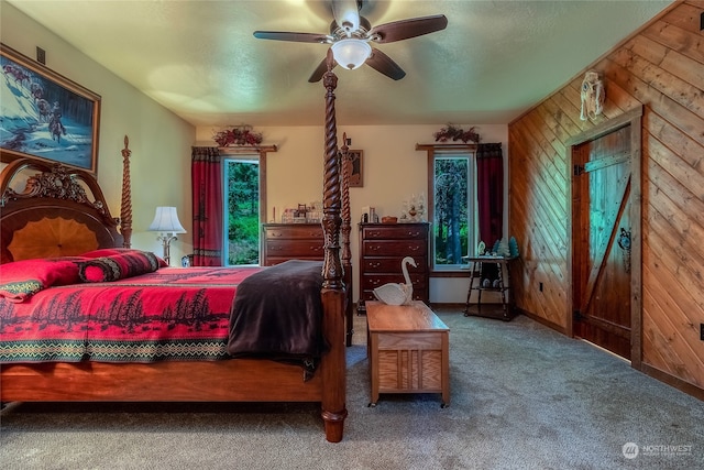 carpeted bedroom with wood walls and ceiling fan