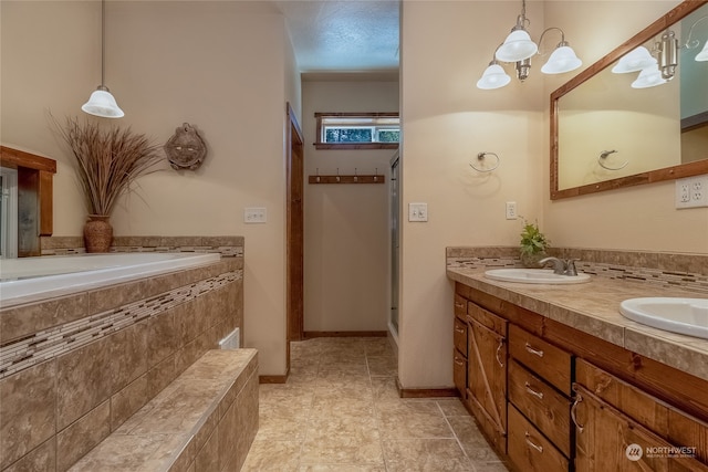 bathroom with a notable chandelier, oversized vanity, double sink, tile floors, and tiled bath