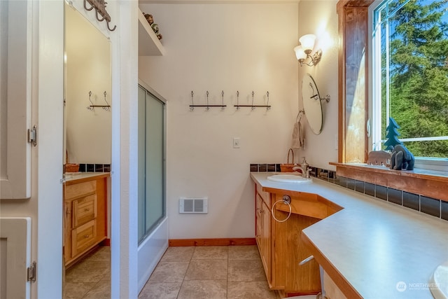 bathroom with combined bath / shower with glass door, vanity, and tile floors